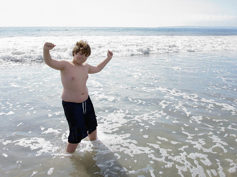 Overweight boy dancing in water at the beach Photograph by Steven Puetzer