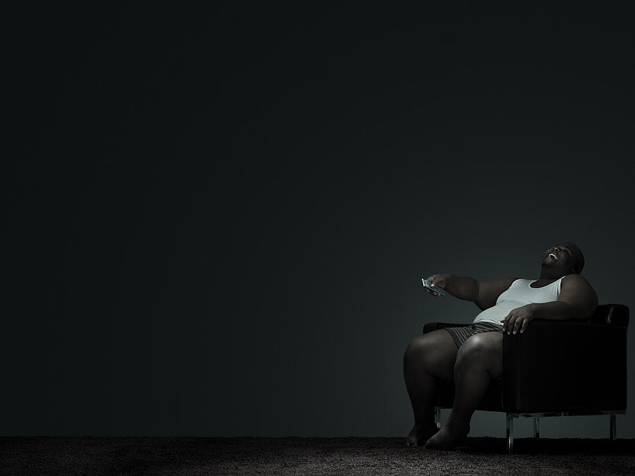 Overweight man watching television Photograph by Image Source