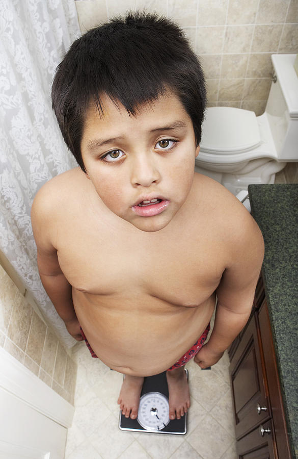 Overweight young boy on scale Photograph by Nycshooter