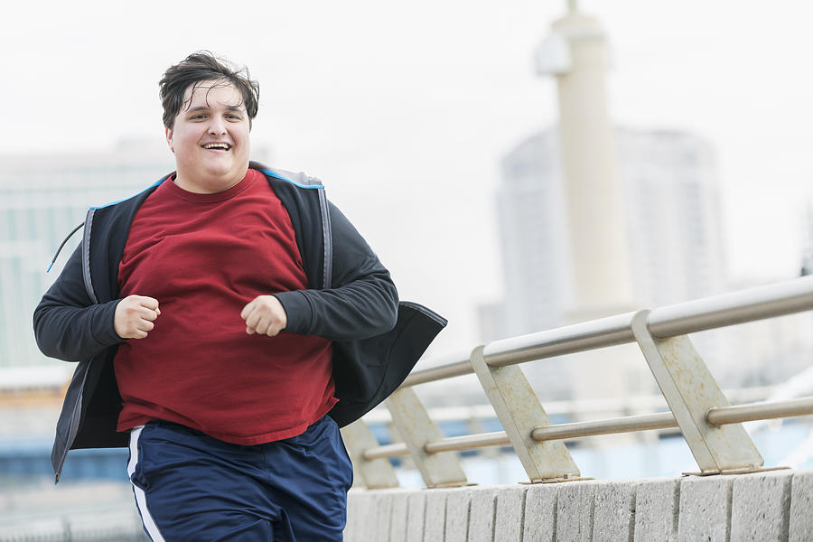 Overweight young man running to lose weight Photograph by Kali9