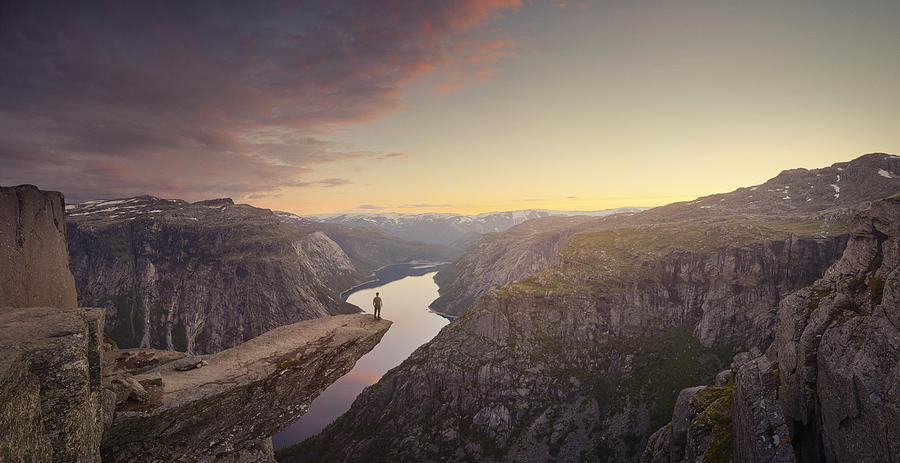 Panoramic of traveller looking out at landscape at sunset, Trolltunga, Norway Photograph by James ONeil