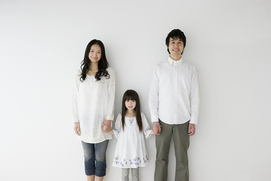 Parents and daughter holding hands, portrait Photograph by Indeed