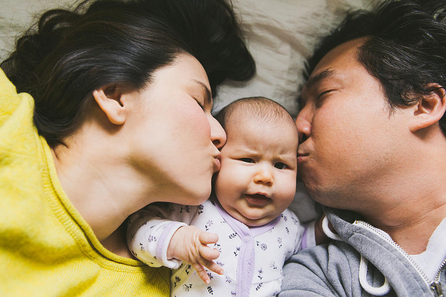 Parents kissing baby Photograph by Tuan Tran