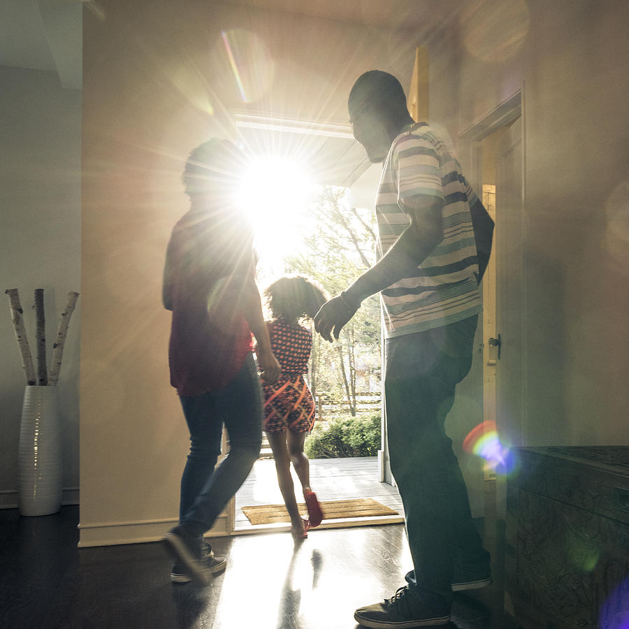 Parents with daughter leaving  the house in bright sunlight Photograph by Johnny Greig