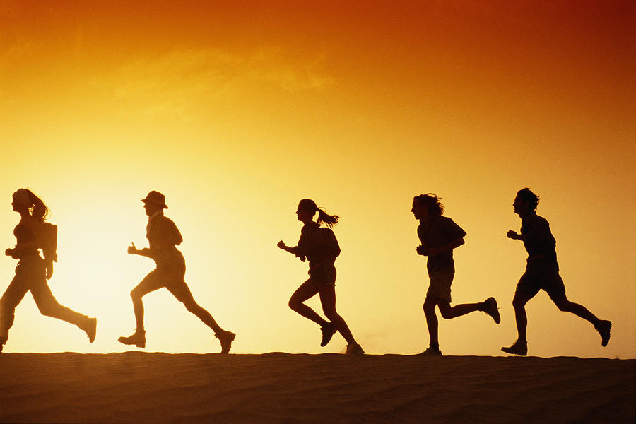 People running in desert at dusk, side view Photograph by David De Lossy