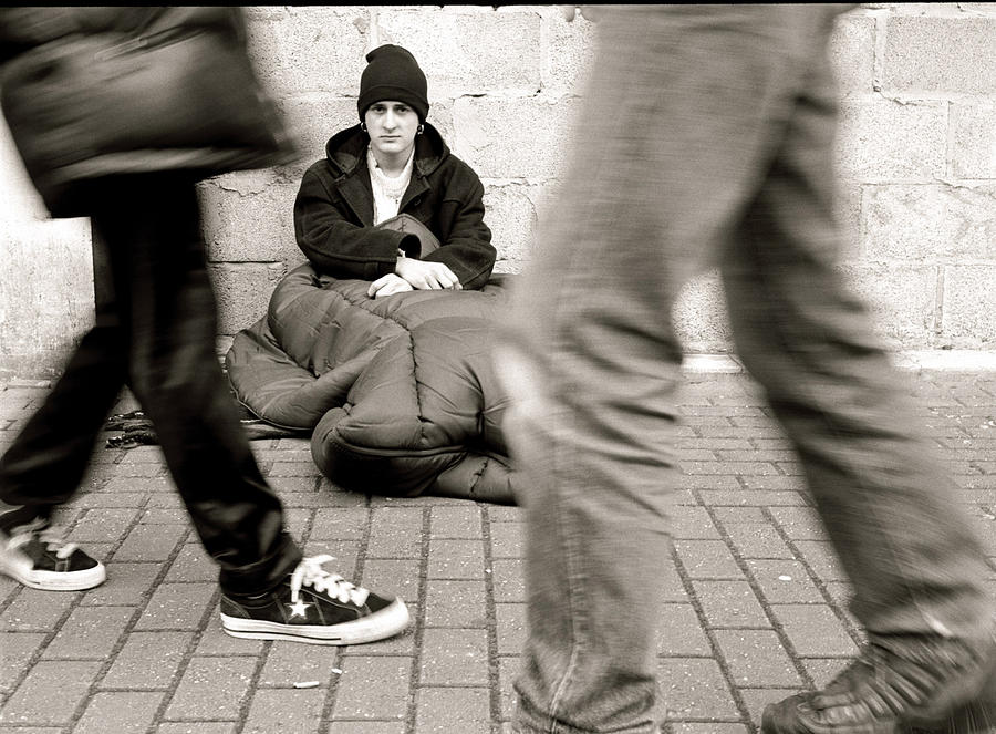 People walking by homless man, sitting on street, (B&W) Photograph by Getty Images