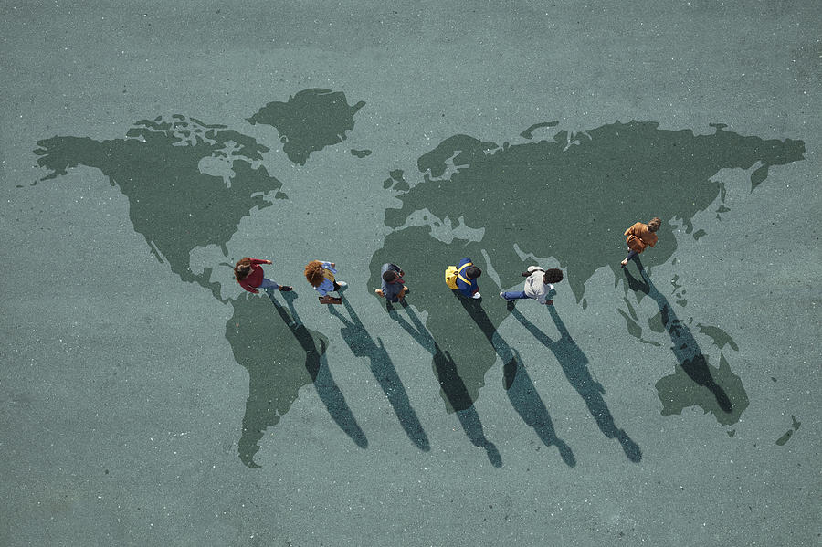 People walking in line across world map, painted on asphalt, front person walking left Photograph by Klaus Vedfelt