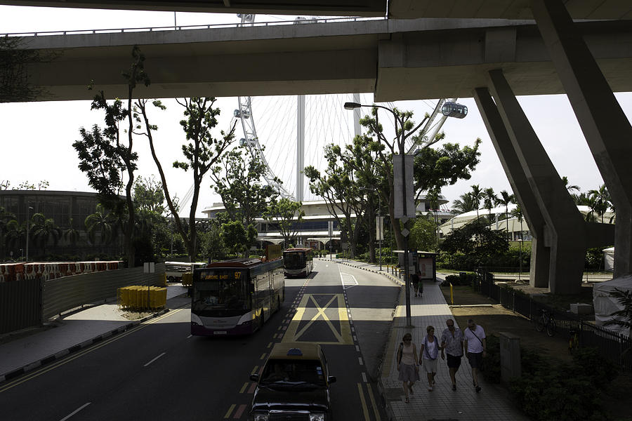 People walking under a flyover on the route leading to the Singapore Flyer Photograph by Ashish Agarwal