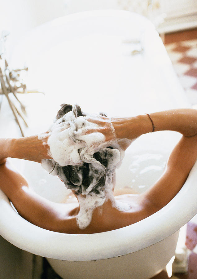 Person in bathtub, shampooing hair, rear view Photograph by John Dowland