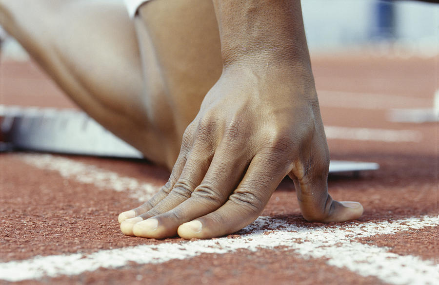 Person kneeling with hands on starting line, Close-up of hand Photograph by Photodisc