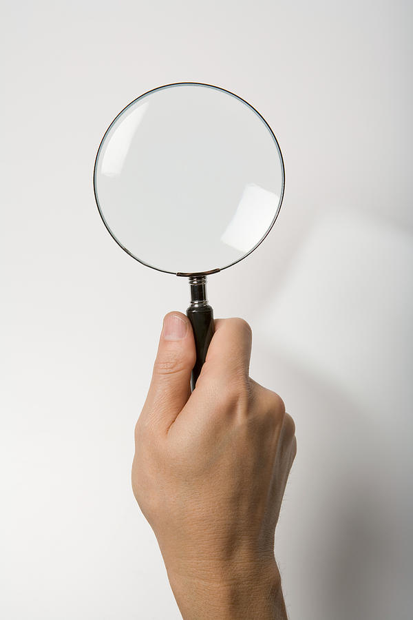 Person with magnifying glass Photograph by Image Source