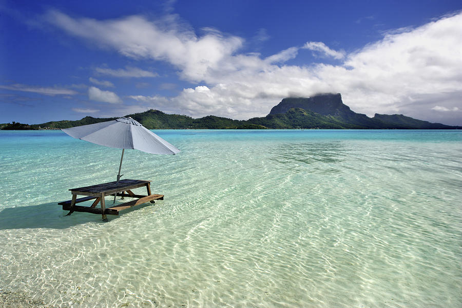 Picnic table and umbrella in clear lagoon Photograph by M Swiet Productions