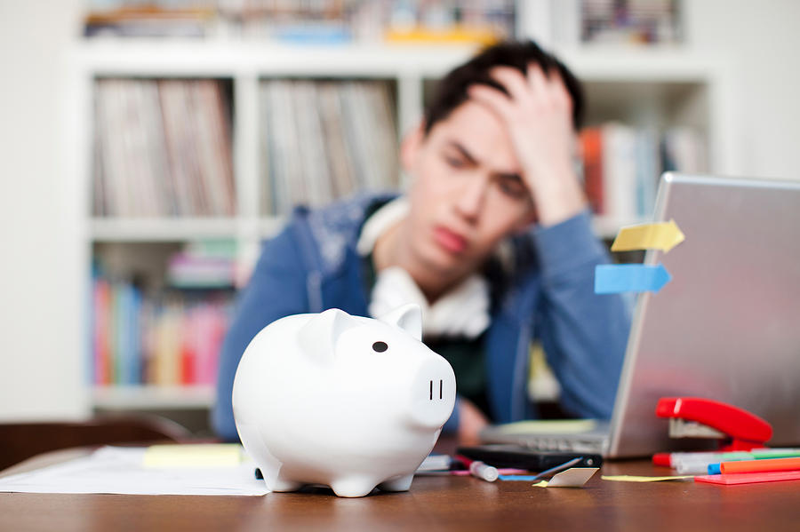 Piggy bank with young man worrying in background Photograph by Alys Tomlinson