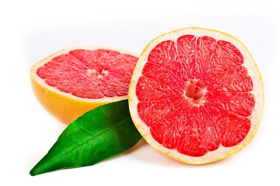 Pink grapefruit cut in half with a green leaf Photograph by Eli_asenova