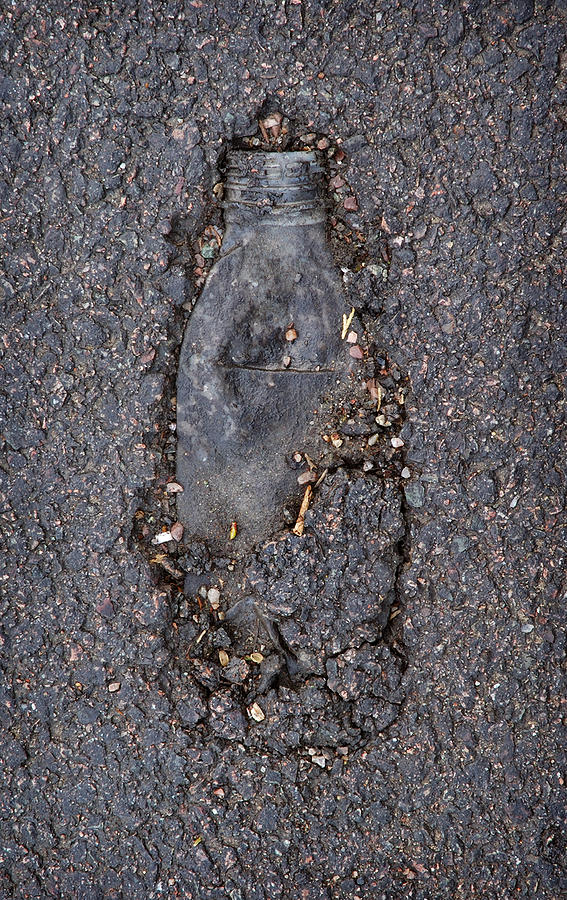 Plastic bottle in tarmac Photograph by Jerry Daniel