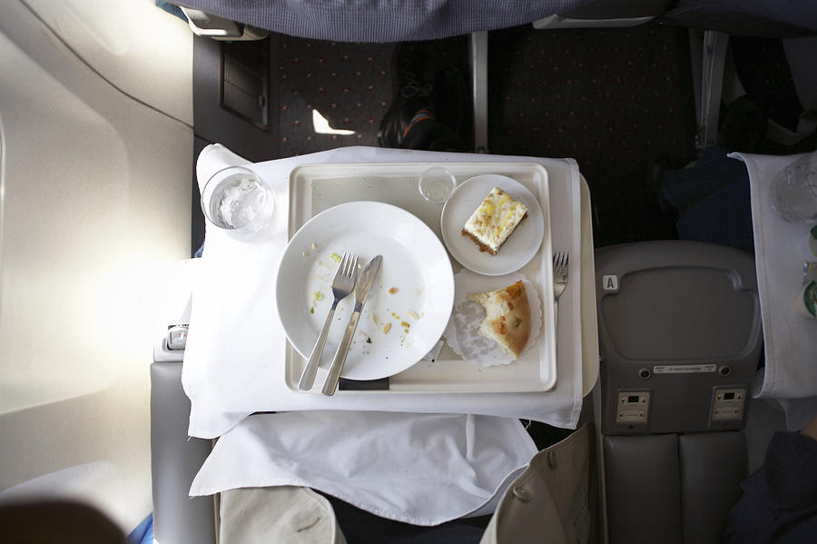 Plate and cutlery on tray table in airplane, overhead view Photograph by Stewart Sutton