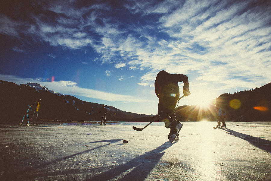 Playing ice hockey on frozen lake in sunset. Photograph by VisualCommunications