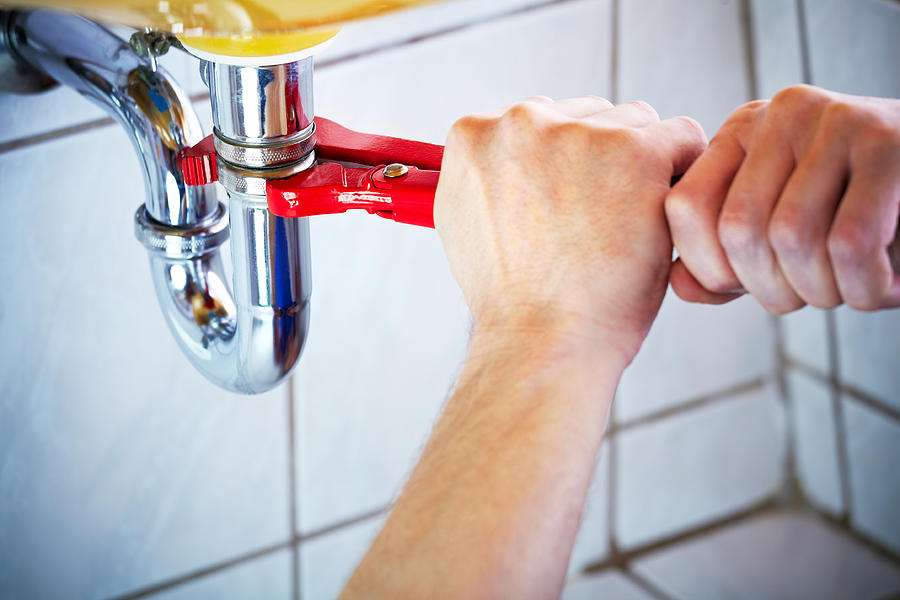 Plumber hands holding wrench and fixing a sink in bathroom Photograph by Deepblue4you