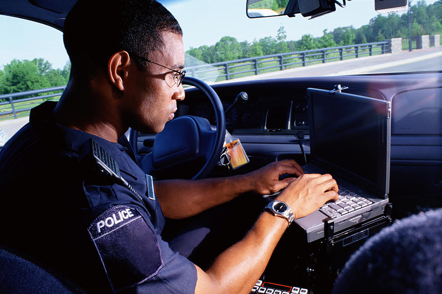 Policeman working on computer in car Photograph by Thinkstock