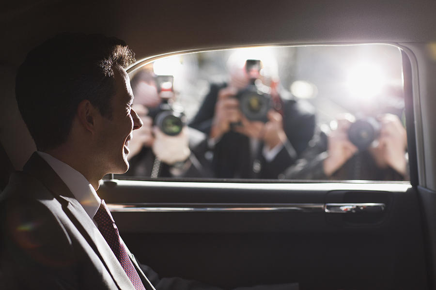 Politician smiling for paparazzi in backseat of car Photograph by Tom Merton