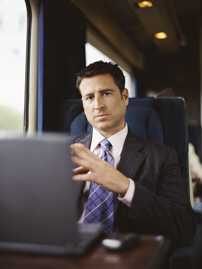 Portrait of a Businessman Sitting on a Seat on a Passenger Train Photograph by Digital Vision.