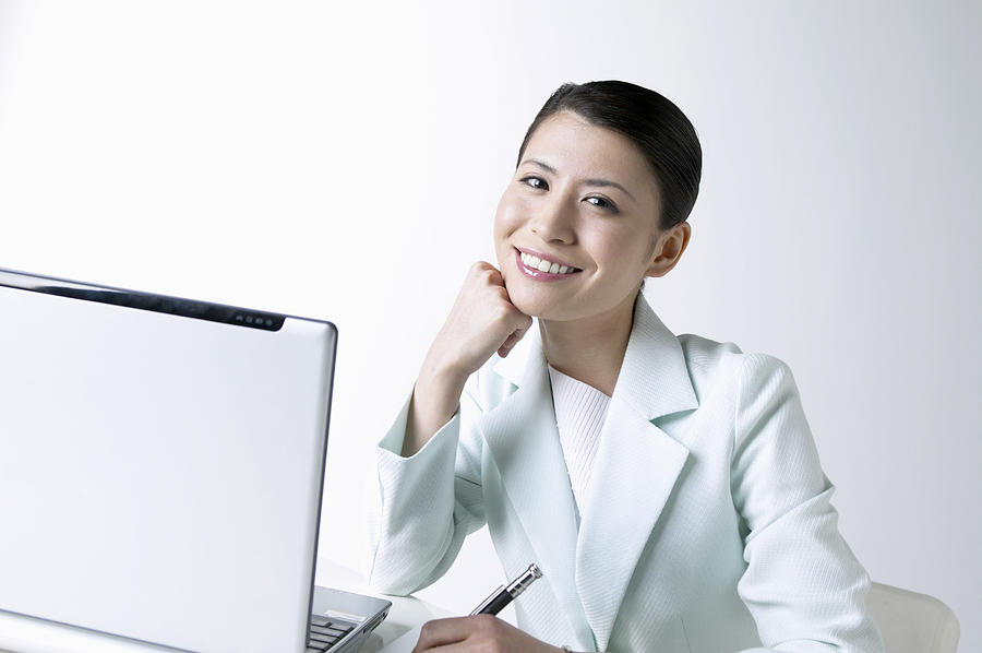 Portrait of a Businesswoman With Her Hand on Her Chin Sitting by a Laptop Photograph by Mash