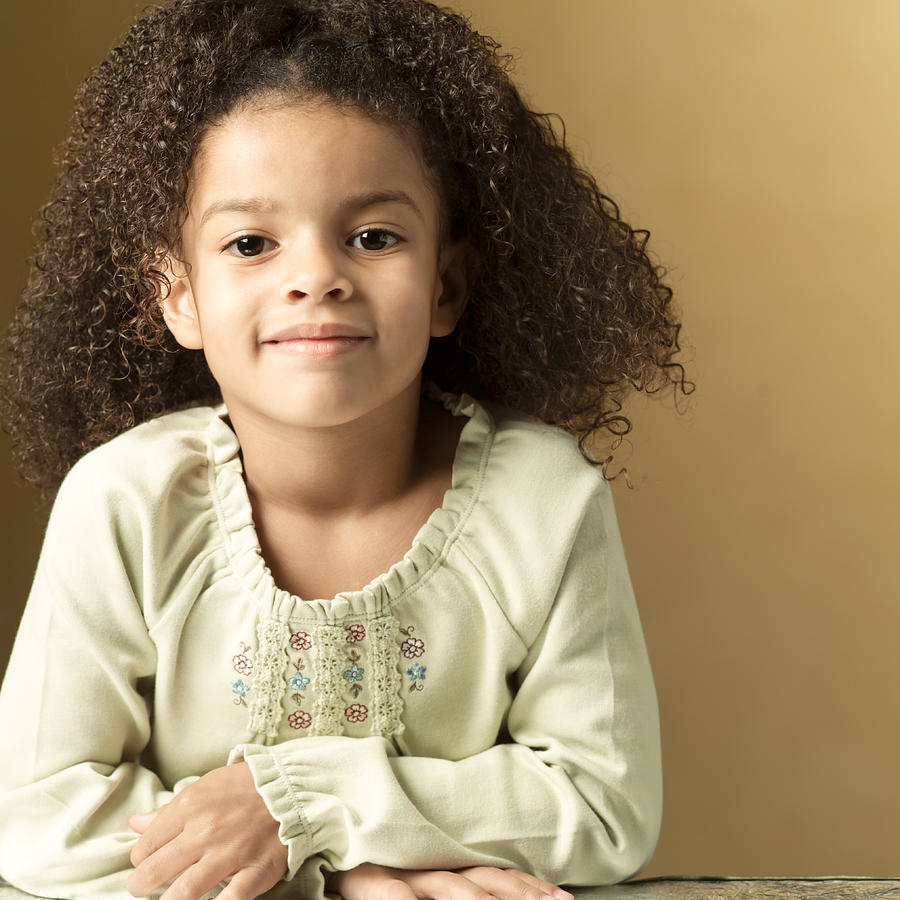 Portrait Of A Cute African American Girl In A Tan Sweater Folds Her Arms And Smiles Slightly Photograph by Photodisc