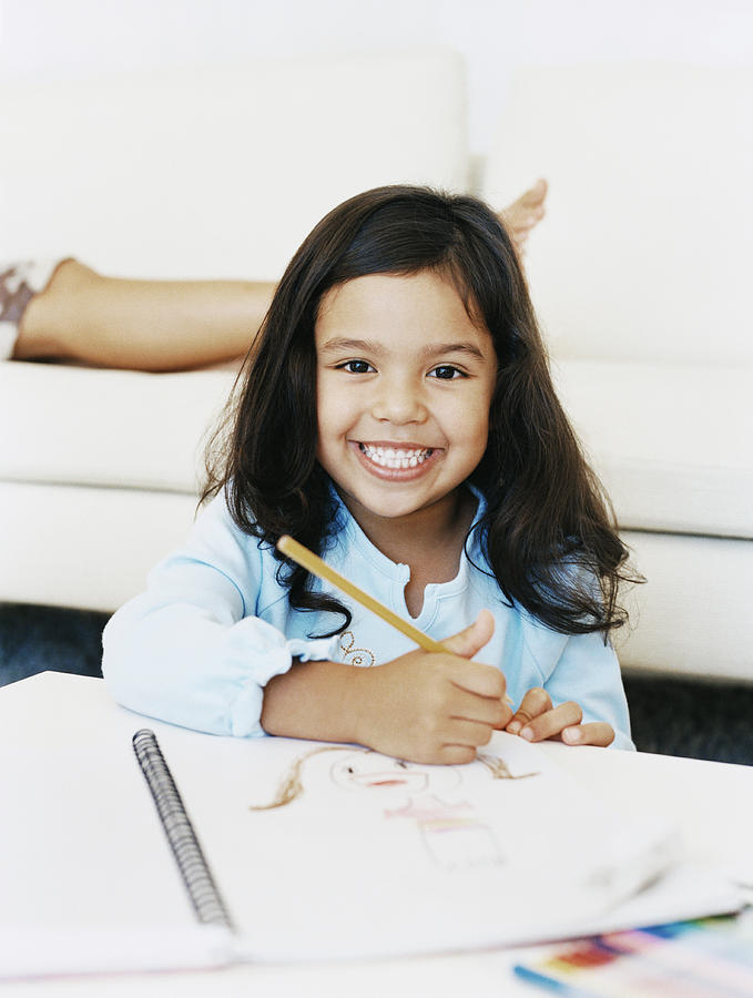 Portrait of a Smiling, Young Girl With a Drawing Book at a Table Photograph by Digital Vision.