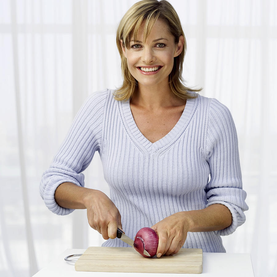 Portrait of a woman chopping onion on a cutting board Photograph by Stockbyte