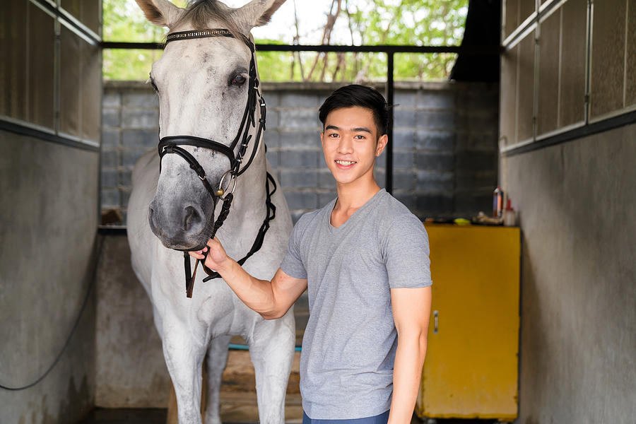 Portrait of a young male horse rider stood with his horse Photograph by JGalione