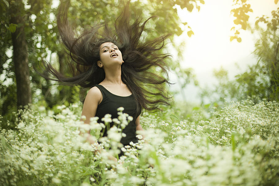 Portrait of Beautiful Asian girl in meadow doing hair toss. Photograph by Gawrav