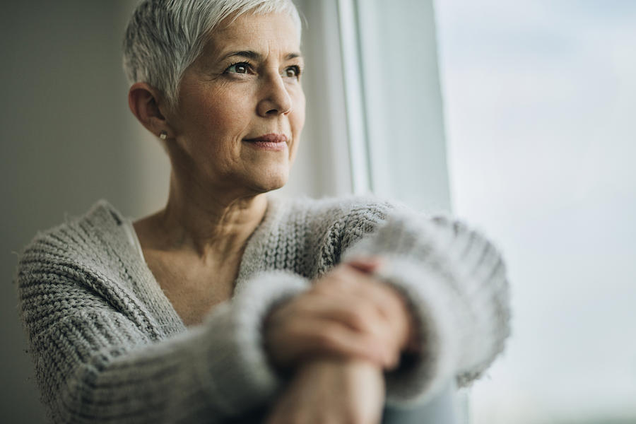 Portrait of beautiful mature woman relaxing by the window. Photograph by Skynesher