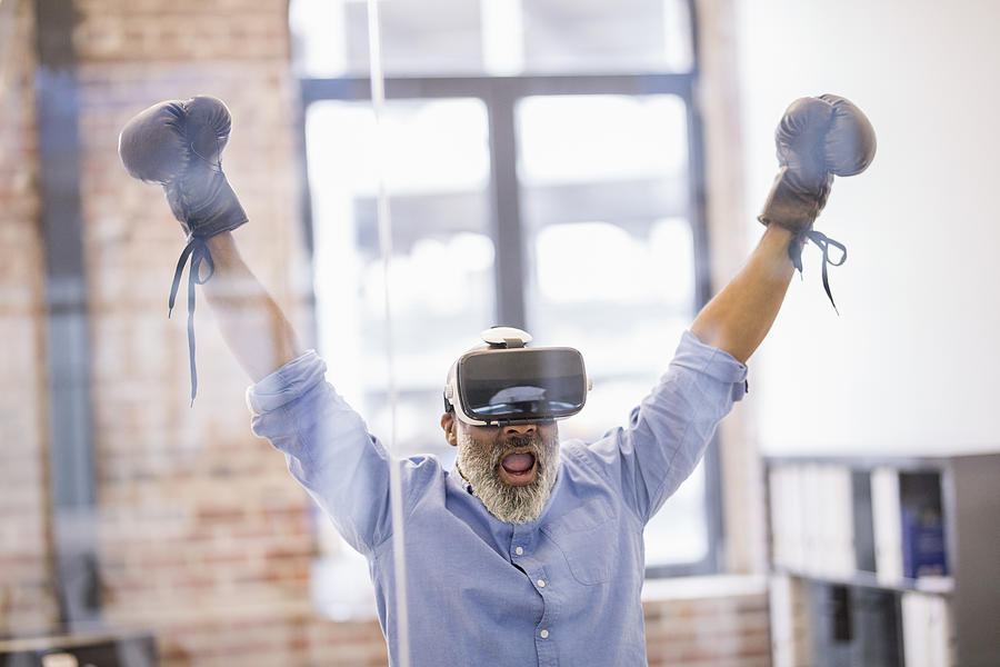 Portrait of businessman with Virtual Reality Glasses and boxing gloves in the office Photograph by Westend61
