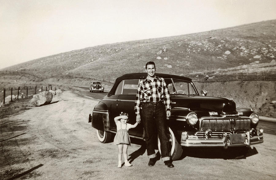 Portrait of Caucasian father and daughter posing near vintage car Photograph by PBNJ Productions
