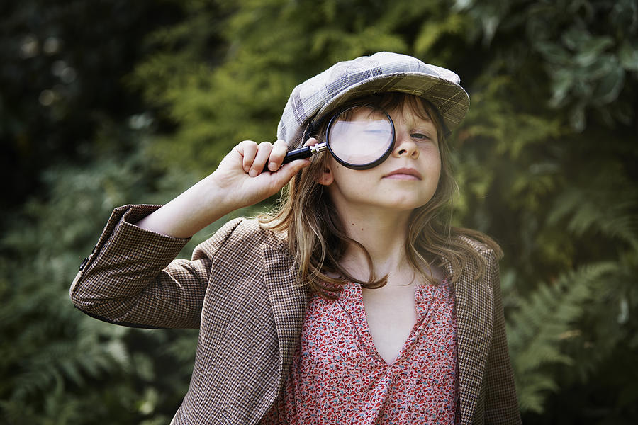 Portrait of girl looking through magnifying glass Photograph by Johner Images
