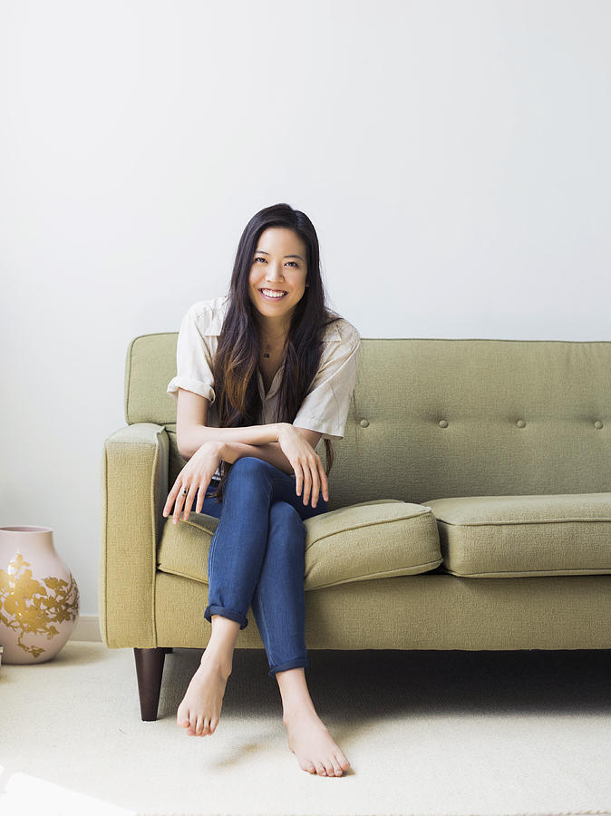 Portrait of happy young woman sitting on sofa Photograph by Jessica Peterson