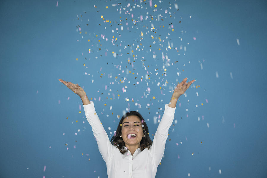 Portrait of laughing woman throwing confetti in the air Photograph by Westend61