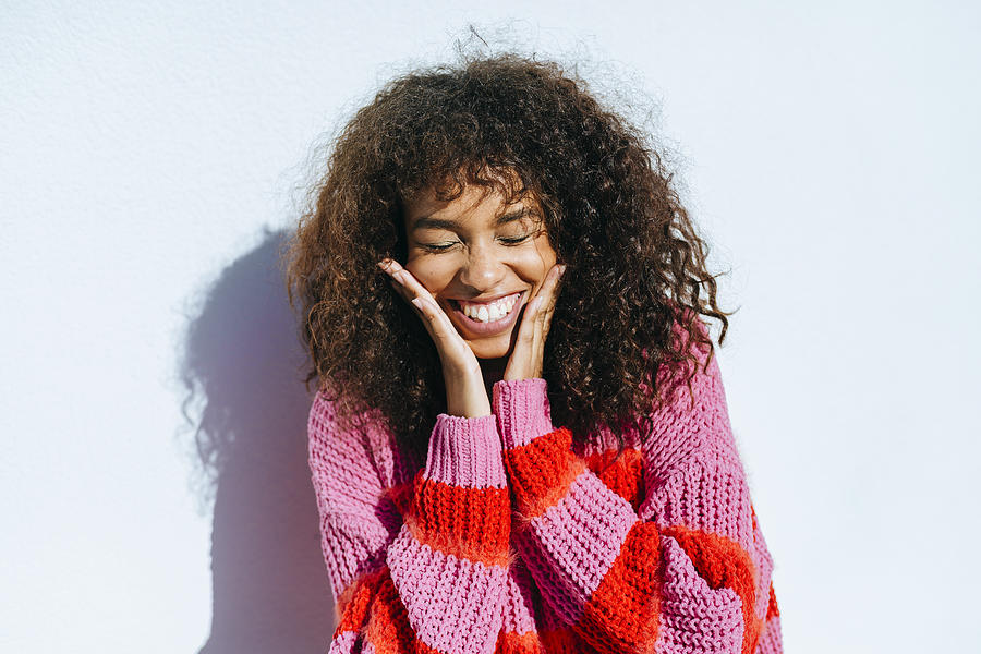 Portrait of laughing young woman with curly hair against white wall Photograph by Westend61