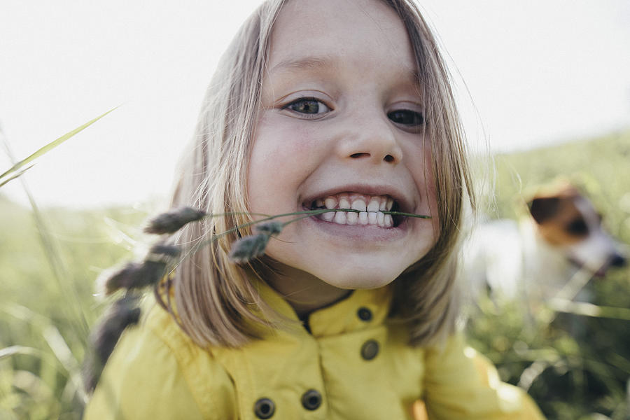 Portrait of little girl on a meadow holding blade of grass with her teeth Photograph by Westend61