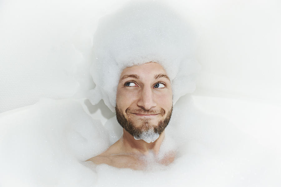 Portrait of man in bath tub, foam on head Photograph by Uwe Krejci