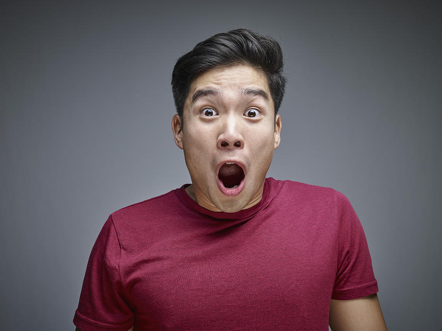 Portrait of shocked young man in front of grey background Photograph by Westend61