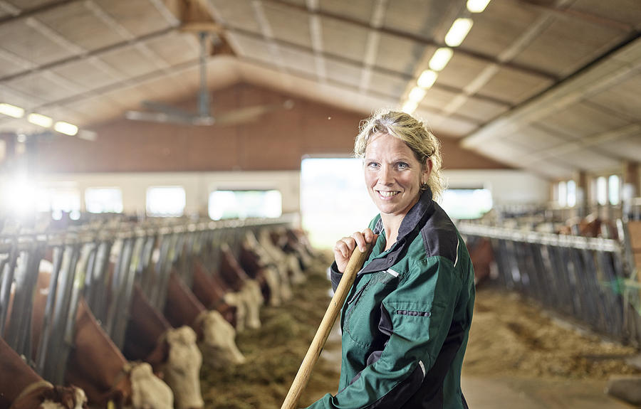 Portrait of smiling female farmer in stable on a farm Photograph by Westend61