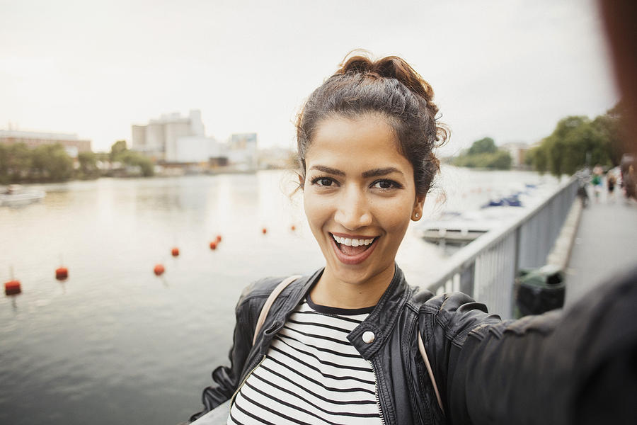 Portrait of smiling woman standing against river in city Photograph by Maskot