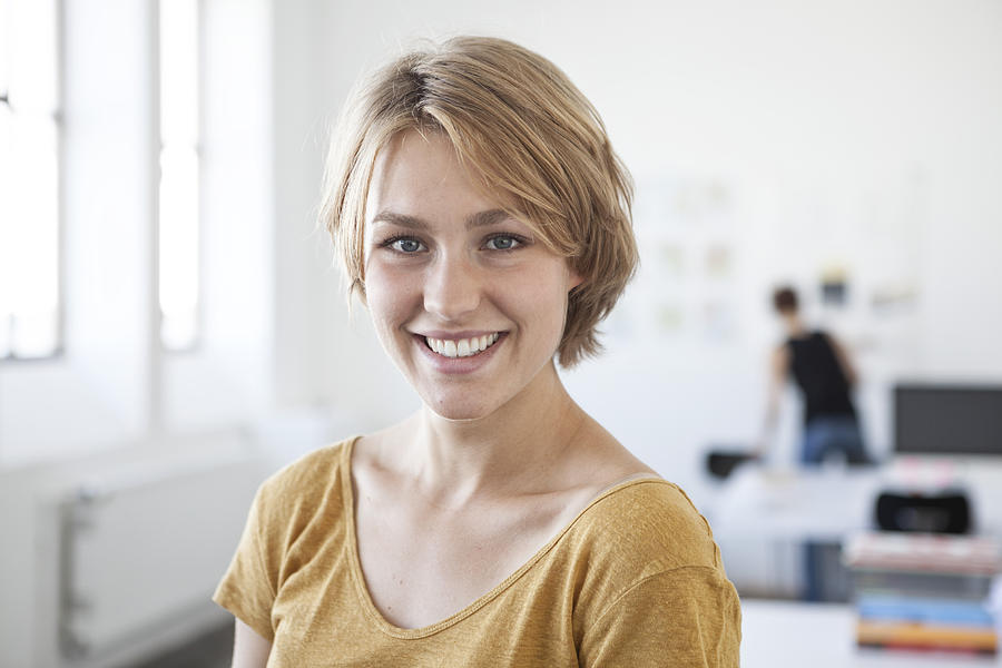 Portrait of smiling young woman in a creative office Photograph by Westend61