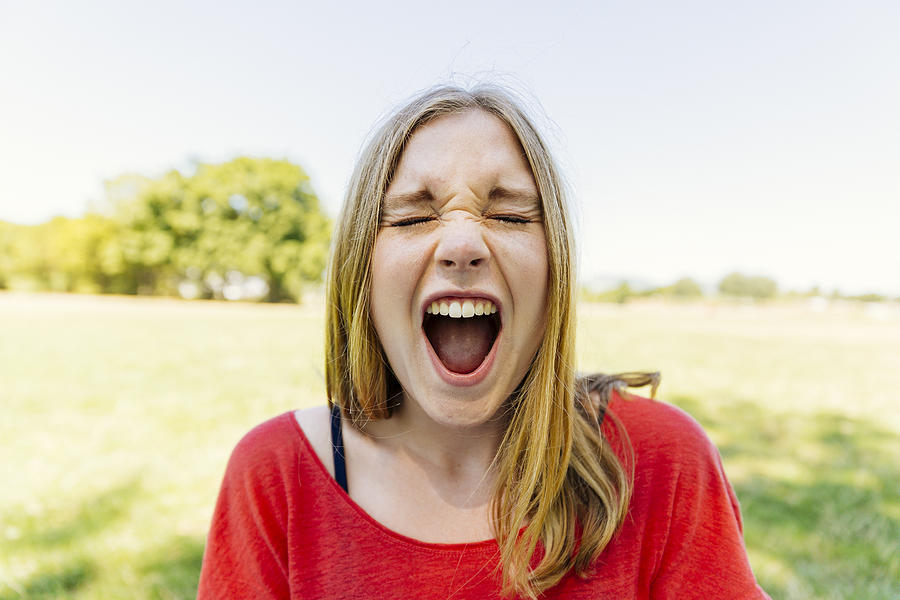 Portrait of teenage girl outdoors screaming Photograph by Westend61