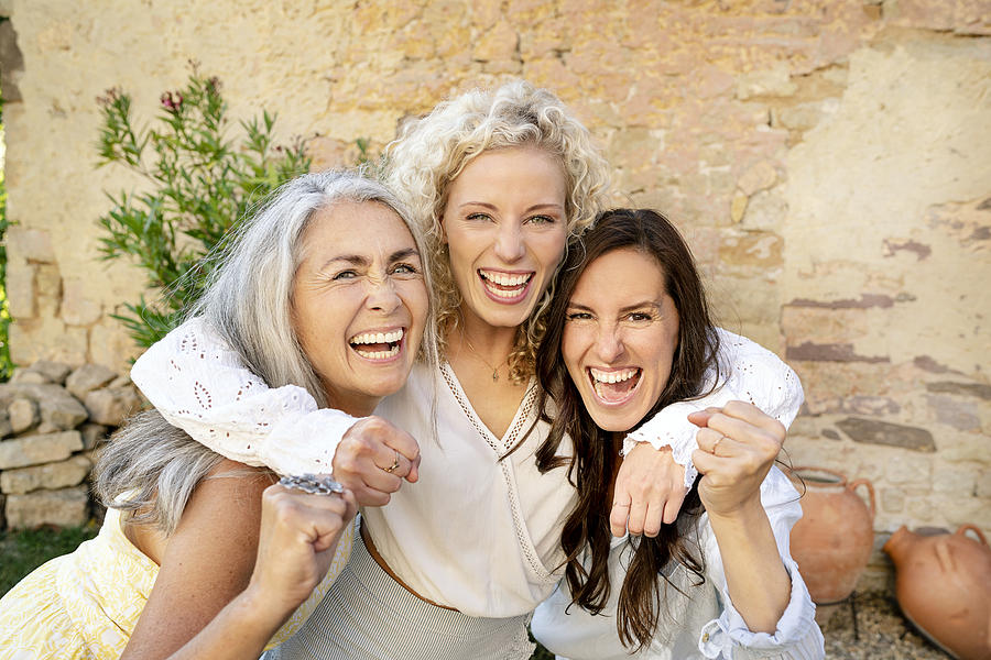 Portrait of three excited women of different age embracing and cheering Photograph by Westend61