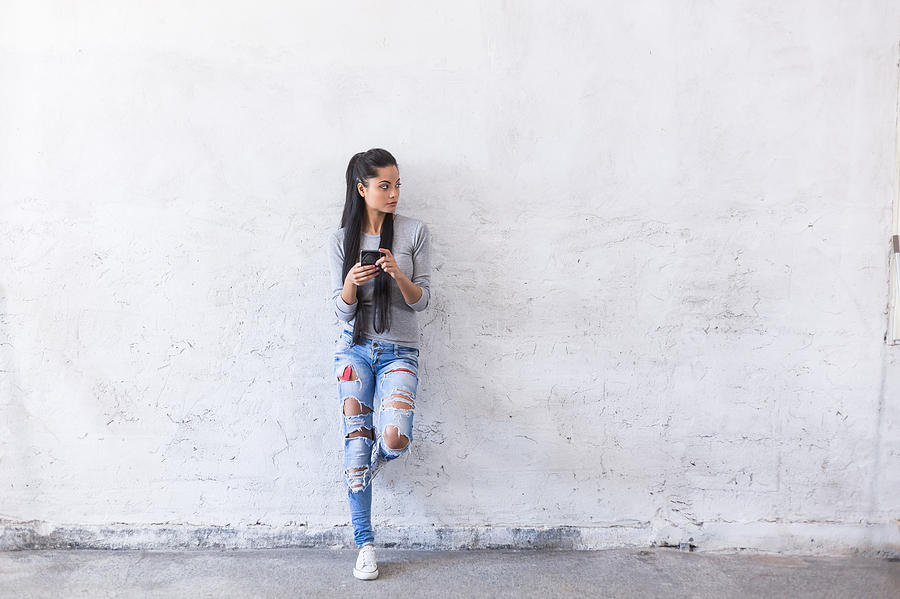 Portrait of young asian woman leaning back on blank wall Photograph by Valentinrussanov