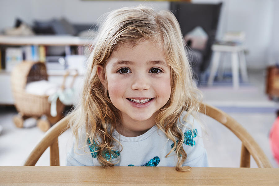 Portrait of young girl, sitting at table, smiling Photograph by Emely