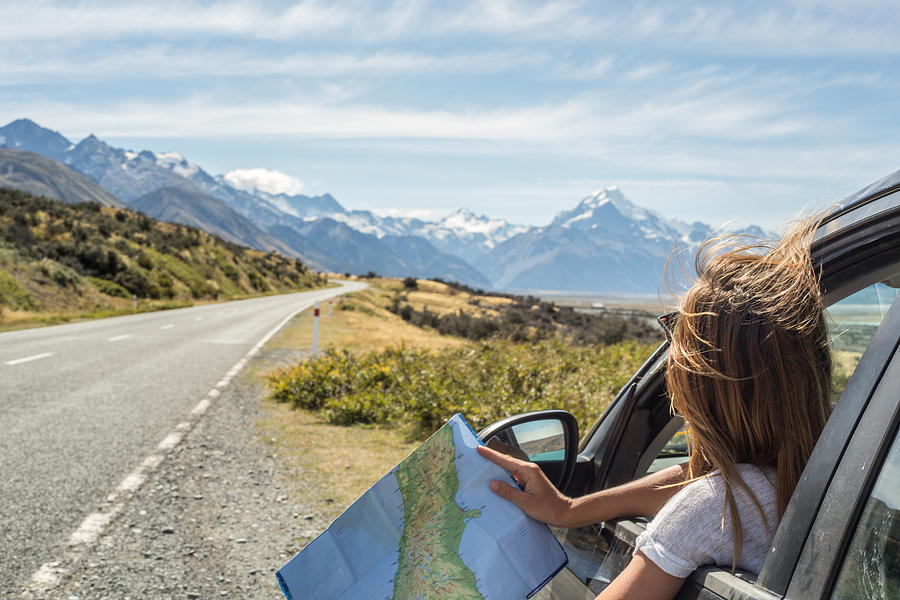 Portrait of young woman in car looking at map Photograph by Swissmediavision
