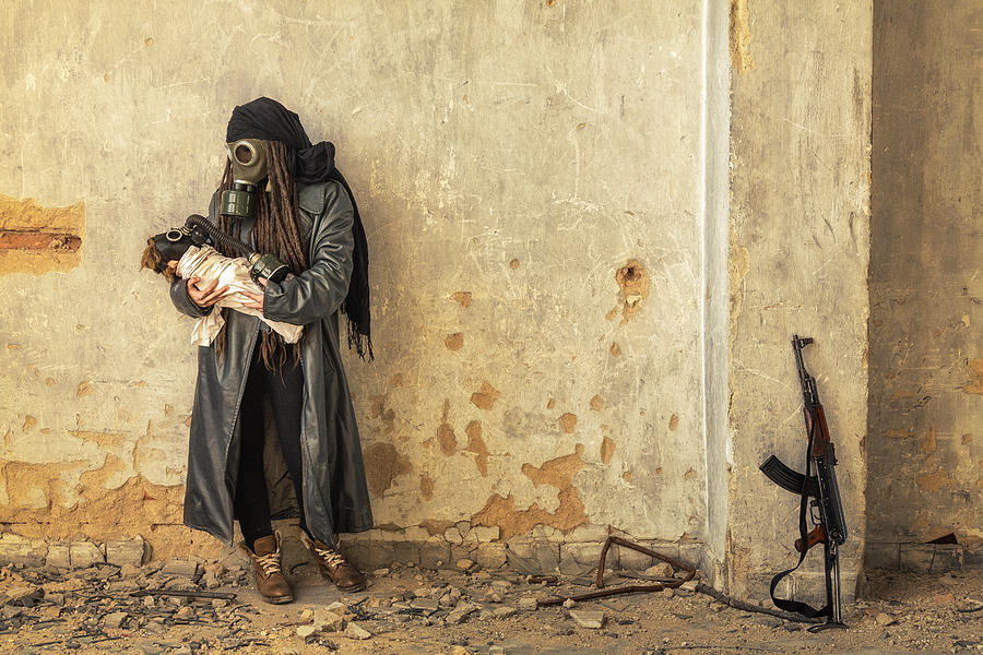Post apocalyptic survivor holding her baby in gas mask Photograph by Peter Zelei Images